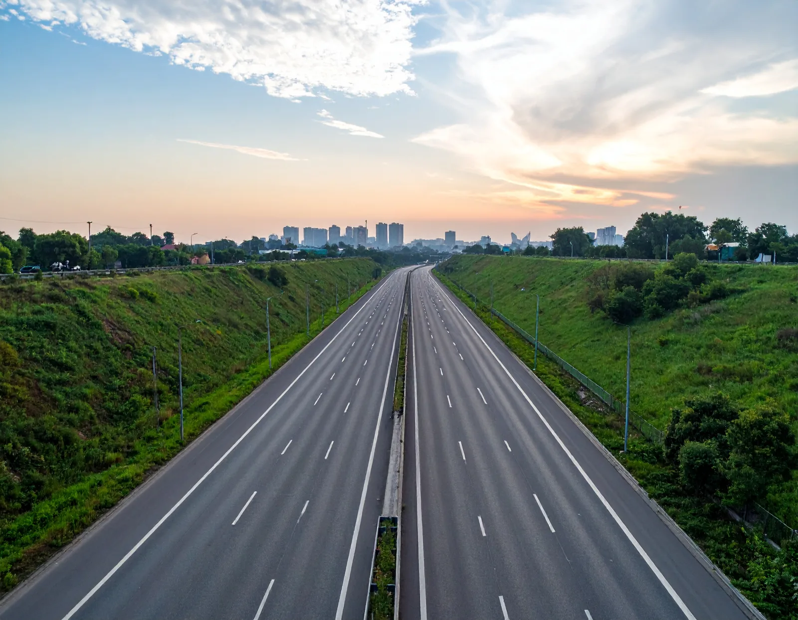 都市へ向かって延びる道路と青空